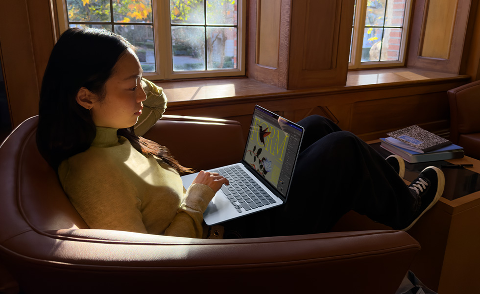 A person sitting in a chair using their MacBook Air