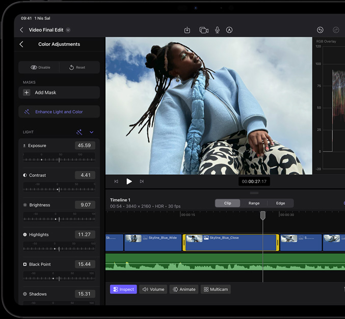iPad Pro, önden dış görünüm, siyah ekran çerçevesi, ekranda mavi ceket ve siyah beyaz baskılı pantolon giymiş bir modelin resminin bulunduğu video düzenleme uygulaması gösteriliyor, solda çeşitli video efektleri ve ayar çubukları ile bir renk ayarlaması paneli açık, altta çok sayıda video klip ve ses parçası içeren zaman çizelgesi yer alıyor