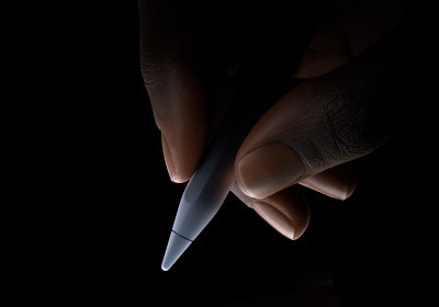 مستخدم يمسك الثلث السفلي من قلم Apple Pro بين الإبهام والسبابة، استعداداً للكتابة.